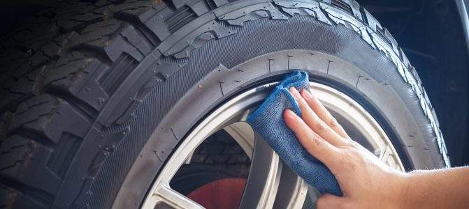 A hand holding a cloth against the rim of a tire.